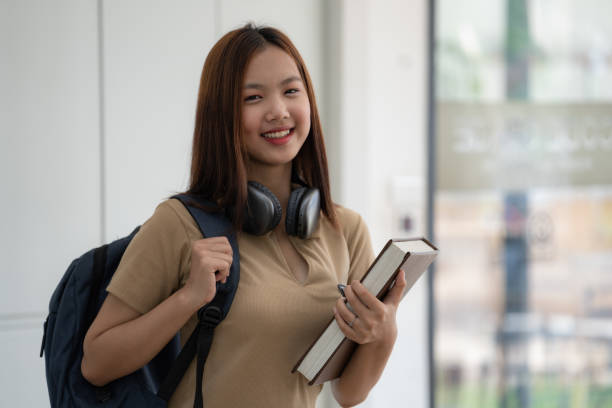 istock An Asian female college student carrying a backpack and holding a book. 1496793723