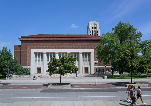 Ann Arbor, MI - August 2022: Students walking on the campus of the University of Michigan, Ann Arbor, with large auditorium building and clocktower