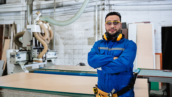 Portrait of carpenter worker doing his job in workshop. Technician handcrafted furniture in furniture factory.