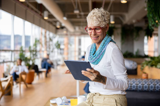 Happy businesswoman smiling at a coworking while using a tablet