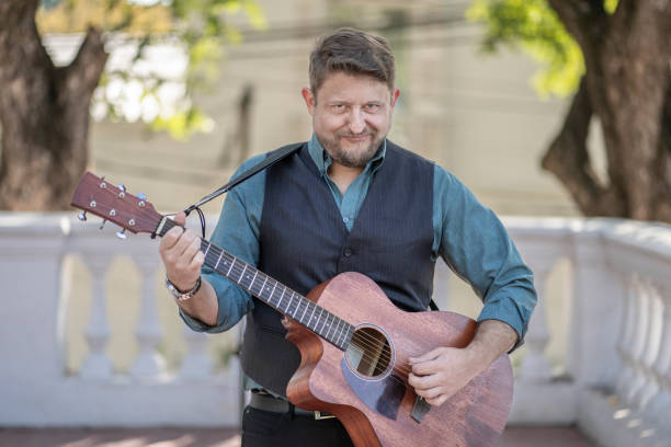 istock Guitarist performing in a park looking at the camera 1496807372