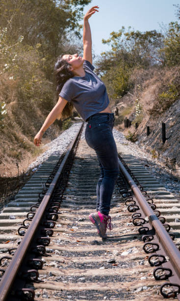 istock Poetic Elegance: Latina Woman's Dance-inspired Pose on Sunny Railroad 1496810161