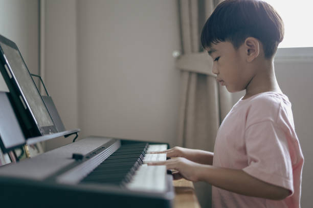 istock Asian boy sitting play keyboard at home 1496810997