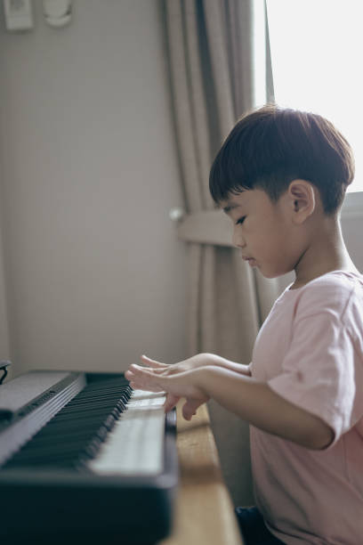 istock Asian boy sitting play keyboard at home 1496810999