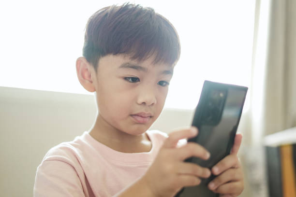 istock Close-up boy sitting using mobile phone at home 1496811067