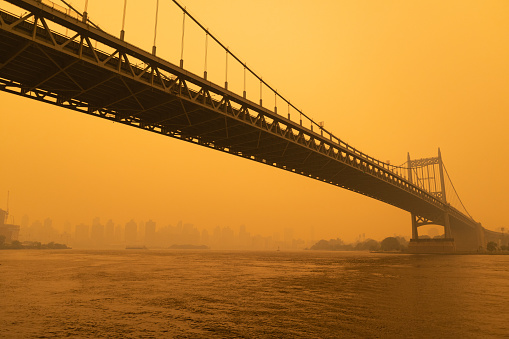 The Triborough Bridge along the East River in New York City with massive air pollution in the sky from wildfires