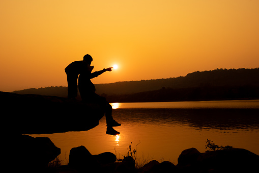 Silhouette of a person on a rock near the reservoir