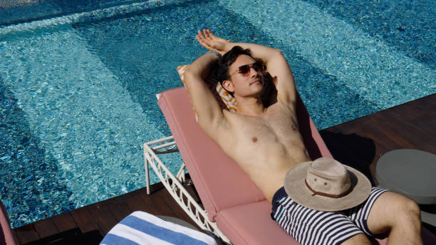 istock Asian male relaxing by the infinity pool in a luxury hotel 1496827148