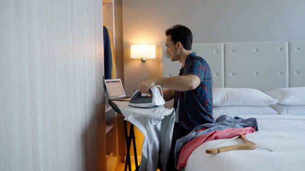 istock Asian male multitasking in his hotel room while on a business call 1496827165