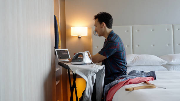 istock Asian male multitasking in his hotel room while on a business call 1496827176