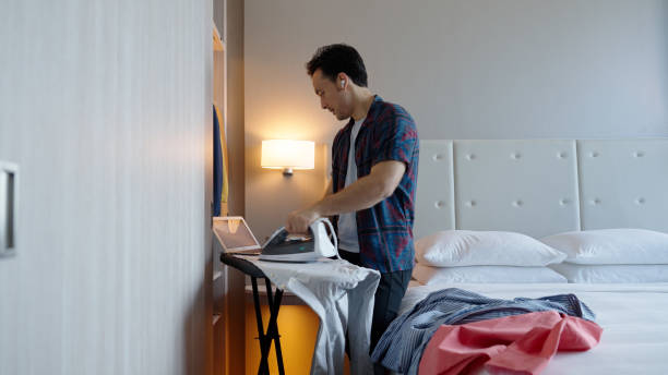 istock Asian male multitasking in his hotel room while on a business call 1496827181