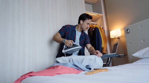 istock Asian male multitasking in his hotel room while on a business call 1496827189