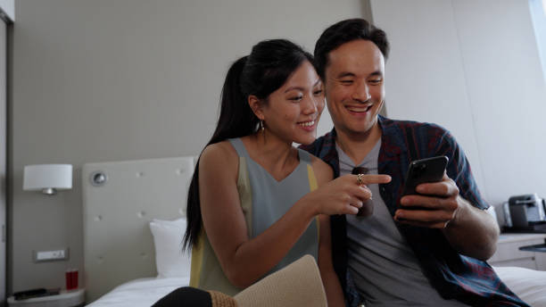 istock Asian couple browsing on their devices in their hotel room while on a holiday trip 1496827237