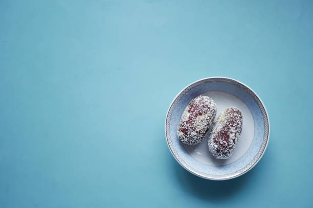 Top down shot of ripe brown dates served in a small clear glass bowl on a wooden texture background.