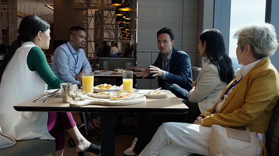 Asian diverse business individuals networking over lunch in a luxury hotel restaurant