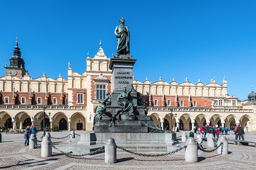 Krakow, Poland - March 11, 2022: Statue of Adam Mickiewicz and Sukiennice buidning with Town Hall in the background in Krakow, Poland.