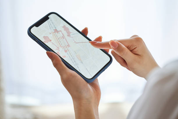 una mujer mirando un mapa en un teléfono inteligente - map cartography travel human hand fotografías e imágenes de stock