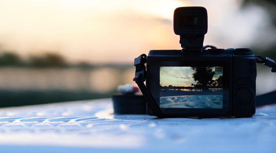 Camera on garden table and photography view camera with blurred focus landscape of sunset sunrise sky cloud.