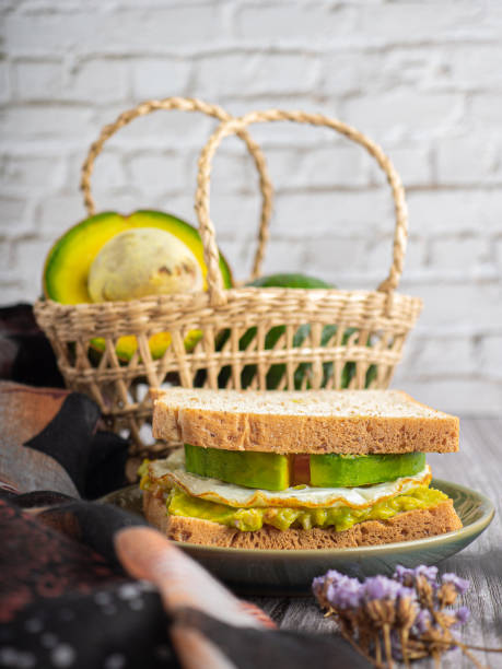 Side view of whole wheat bread and guacamole with fried egg and avocado sliced