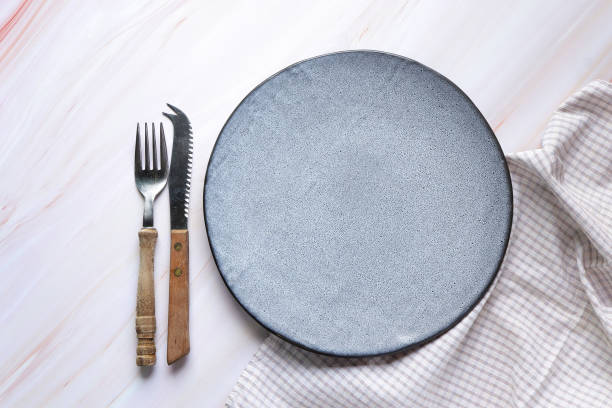 istock Empty grey ceramic plate and retro fork and knife on the table. classic grey plate and napkin, Top view with copy space. 1496843532