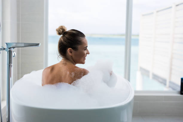istock Back view of happy woman taking a bubble bath. 1496844242