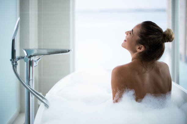 istock Back view of happy woman taking a bubble bath. 1496844301