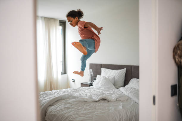 istock Funny African Kid Girl Jumping On Bed 1496845263