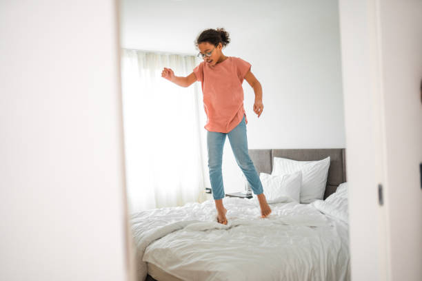 istock Mixed-Race Girl Joyfully Jumping On Bed 1496845271