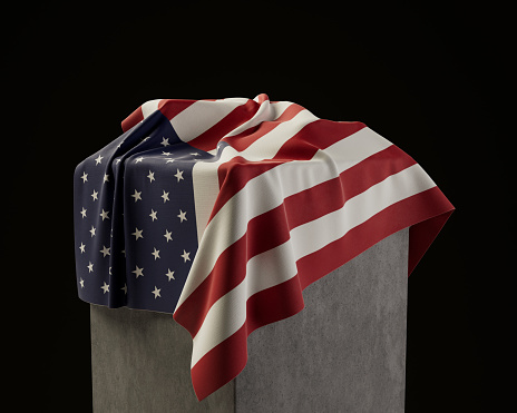 An american flag draped over a stone plinth on an isolated dark studio background - 3D render