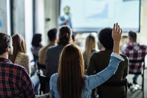 istock Back view of creative woman asking a question on education event in the office. 1496846678