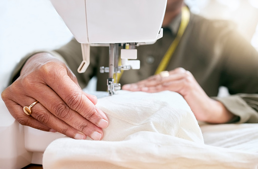 Tailor, woman hands and sewing machine for clothes fabric, luxury apparel or creative design in studio workshop atelier. Startup small business designer, service and sewer working on fashion outfit