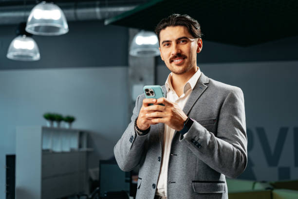 istock Handsome young arab man in formal wear using smartphone in office 1496847663