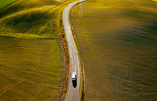Car traveling on a country road through  colorful agricultural fields.