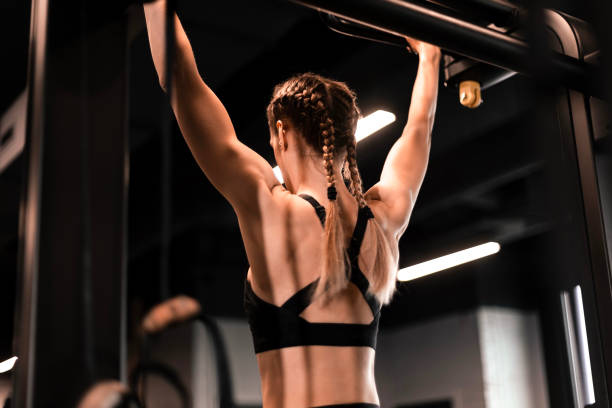 istock Women doing pull ups training arms in the gym. Upper body training. 1496849622