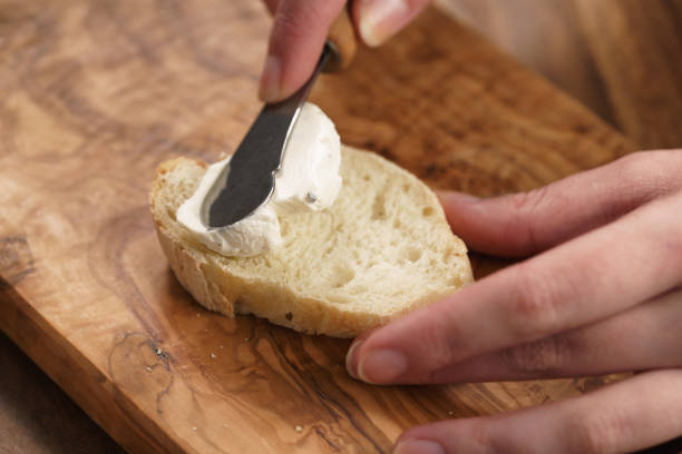 istock young female hands spreading cream cheese on baguette 1496849731