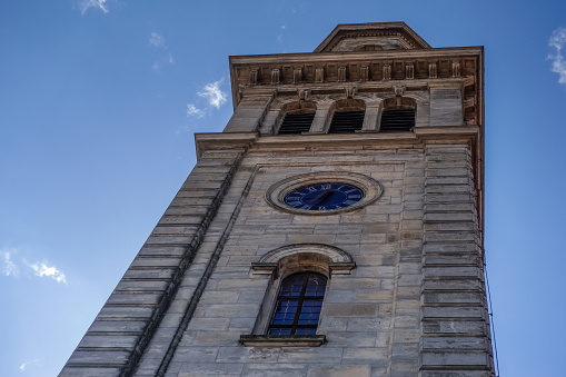 high tower from a church with a clock and blue sky with white clouds detail view