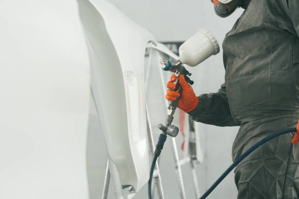 istock Auto painter painting a car with vaporizer gun inside a paint booth 1496850804