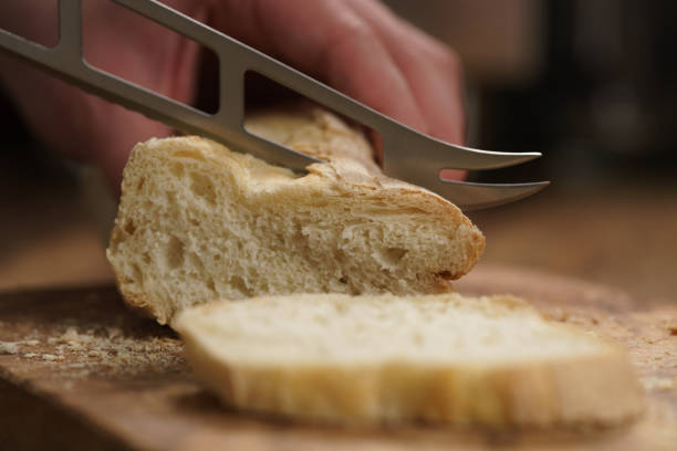 istock young female hands slicing fresh baguette on cutting board closeup 1496851354