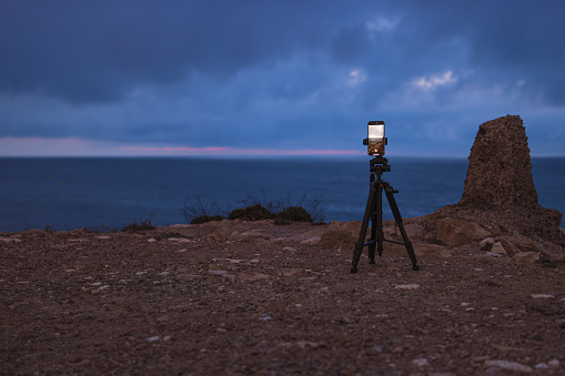 The smartphone camera is on a tripod, photographing a picturesque evening sunset over a tropical sea and a mountain. Photographing the sunset and sunrise of the natural landscape against the blue sky using a mobile phone