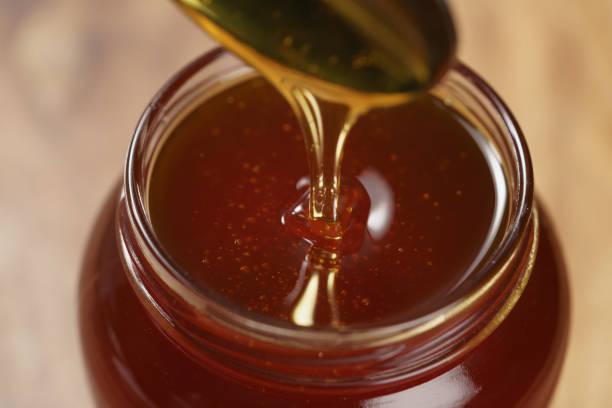 istock pouring organic honey from spoon into glass jar 1496853778