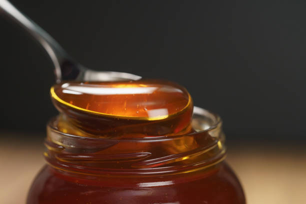 istock scooping organic honey with spoon from glass jar 1496854980