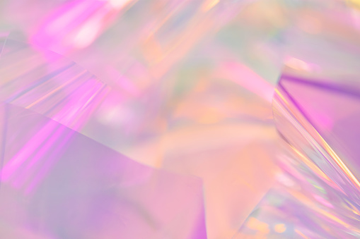 Blurred closeup of ethereal pastel neon pink, purple, lavender, orange, yellow holographic metallic foil background. Abstract modern surreal futuristic disco, rave, techno, festive dreamlike backdrop