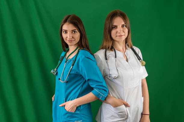 istock two beautiful young female nurses standing smiling in med uniform on isolated background 1496858549
