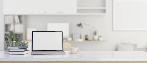 istock A laptop mockup on white table over blurred modern white office in background. 1496860678