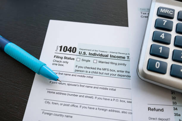 istock 1040 tax form with pen and calculator on office desk 1496861608