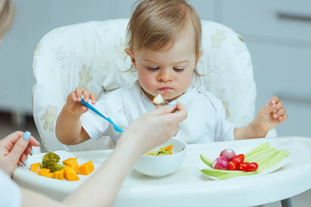 istock Mother teaching baby how to eat by himself. 1496861749