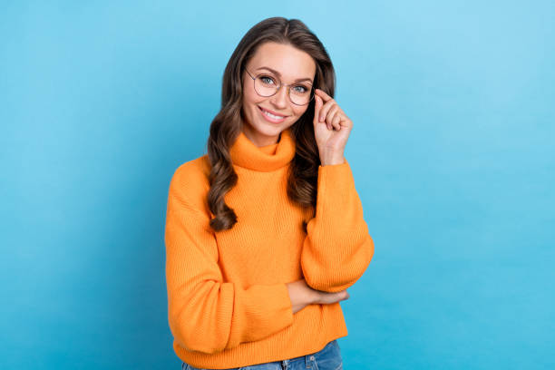 Photo of adorable smart woman wear orange sweater smiling arm spectacles isolated blue color background stock photo