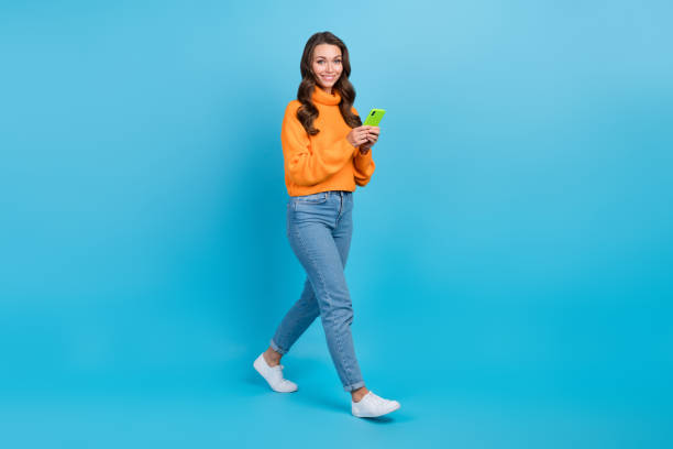 istock Full length photo of shiny pretty lady dressed orange pullover writing sms twitter telegram facebook isolated blue color background 1496867042