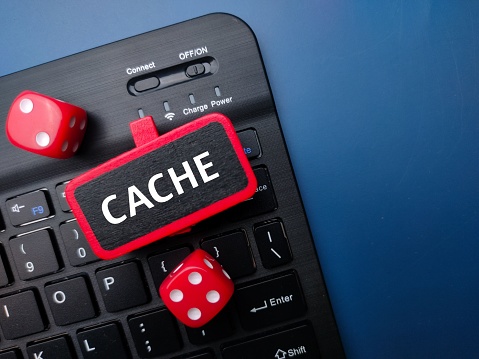 A keyboard and red dice with the word CACHE - Business concept