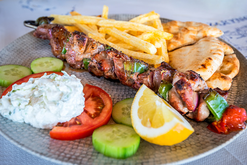 Greek pork Souvlaki with tzatziki sauce and fresh vegetables, grilled kebabs